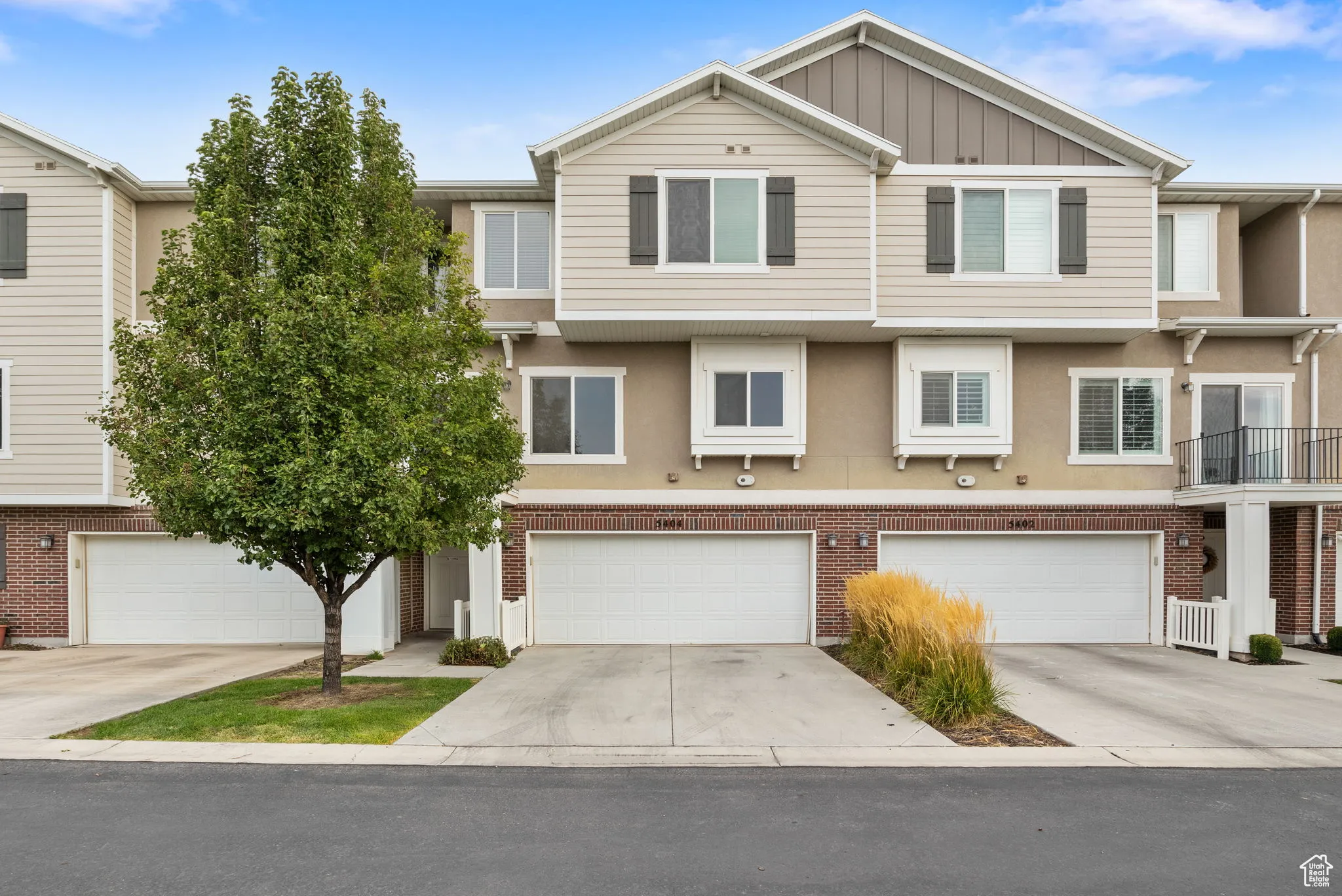 View of front of house featuring driveway, board and batten siding, brick siding, and stucco siding