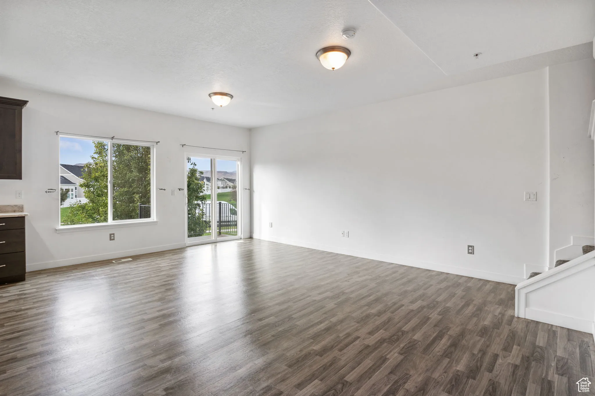 Unfurnished living room featuring dark wood finished floors and baseboards