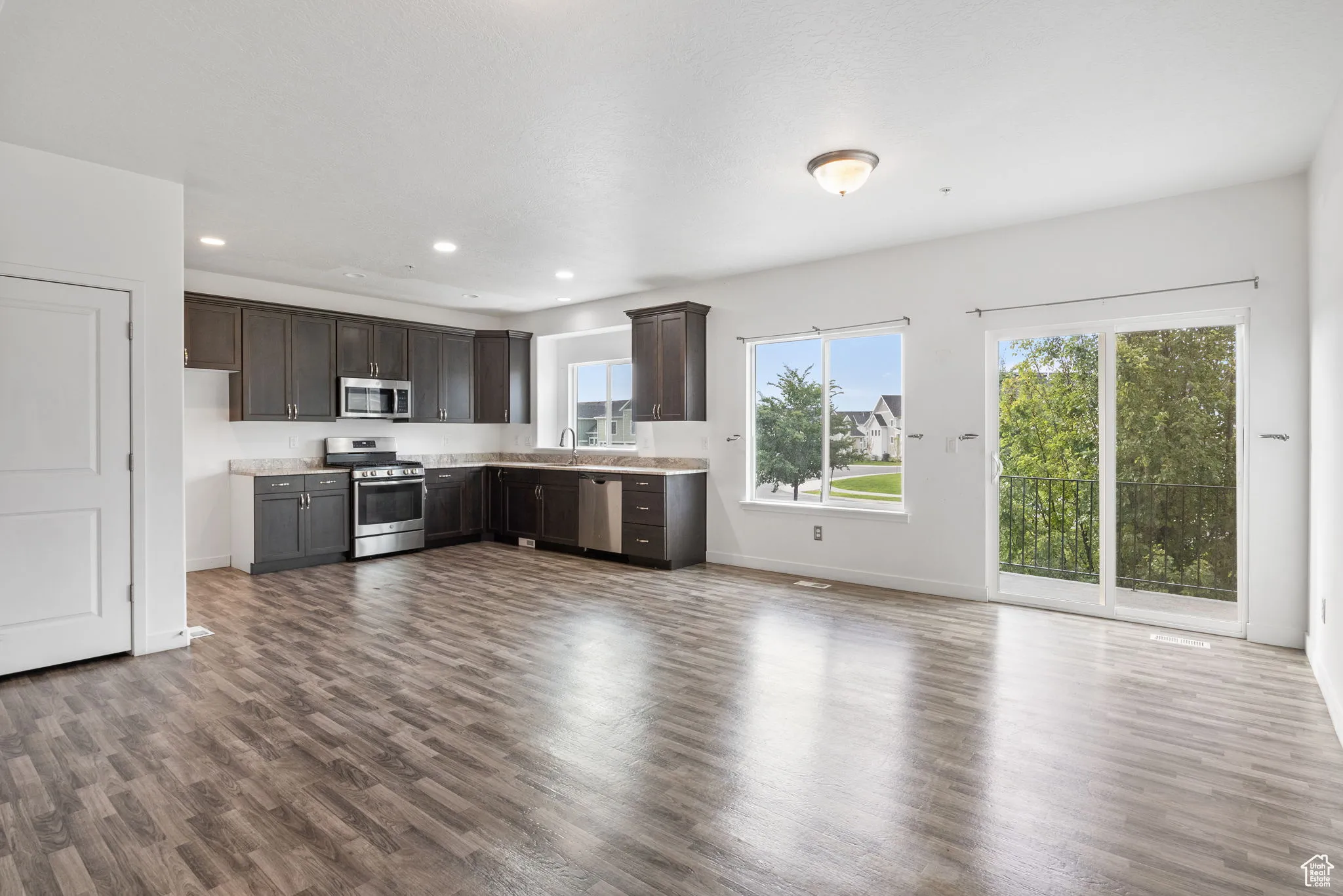 Kitchen featuring dark wood-style floors, dark brown cabinetry, stainless steel appliances, recessed lighting, and open floor plan