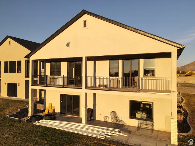 Rear view of house featuring stucco siding, a patio area, and a balcony