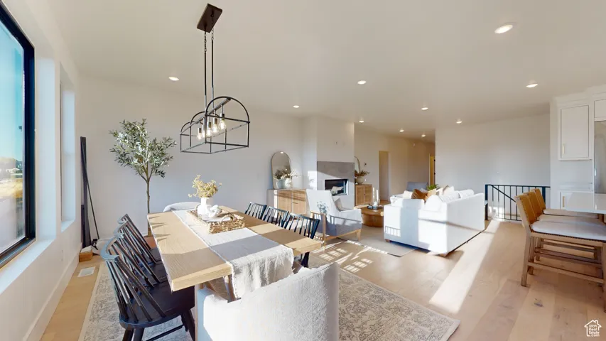 Dining area featuring light wood finished floors, recessed lighting, a chandelier, and a fireplace