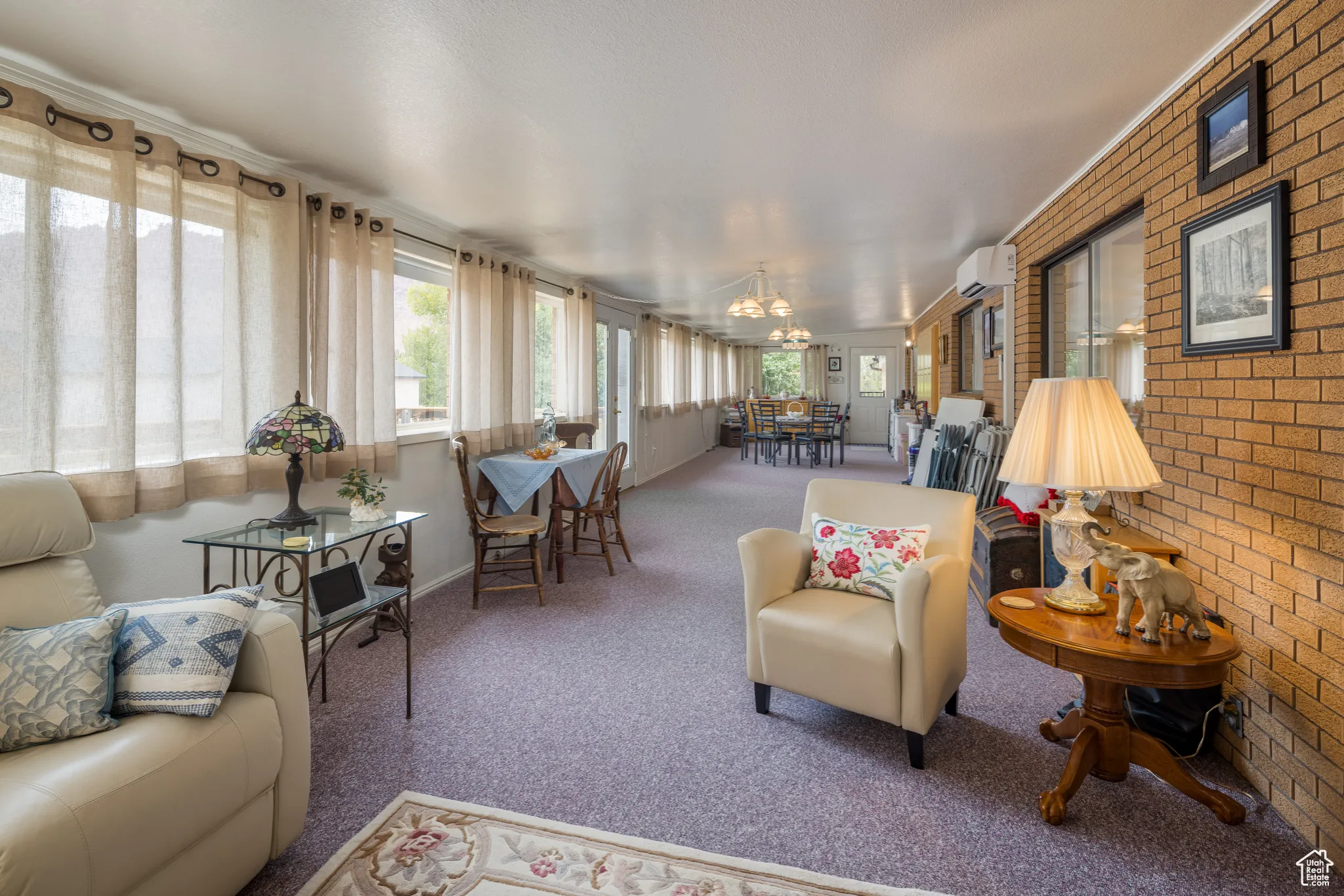 Sunroom / solarium featuring carpet flooring, plenty of natural light, brick wall, and a wall mounted AC