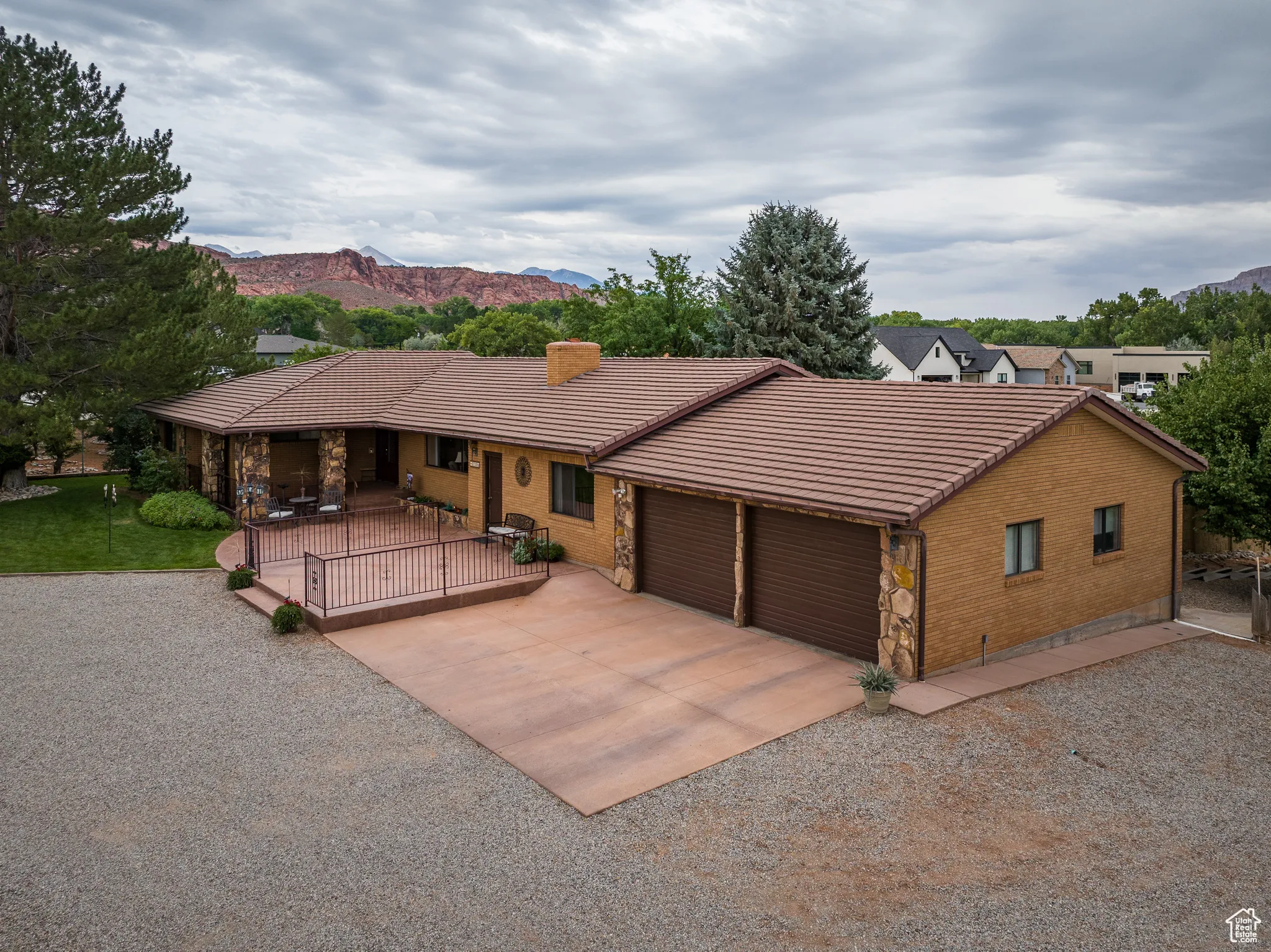 View of front of property with stone siding, concrete driveway, an attached garage, a tile roof, and a mountain view