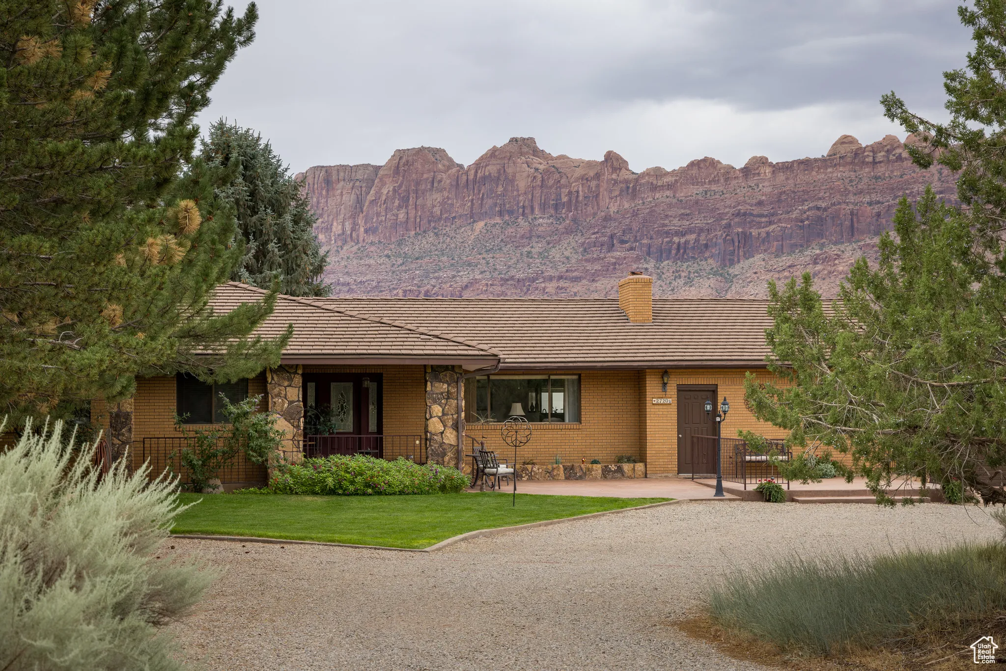 Ranch-style house featuring a chimney, brick siding, a front lawn, a mountain view, and stone siding