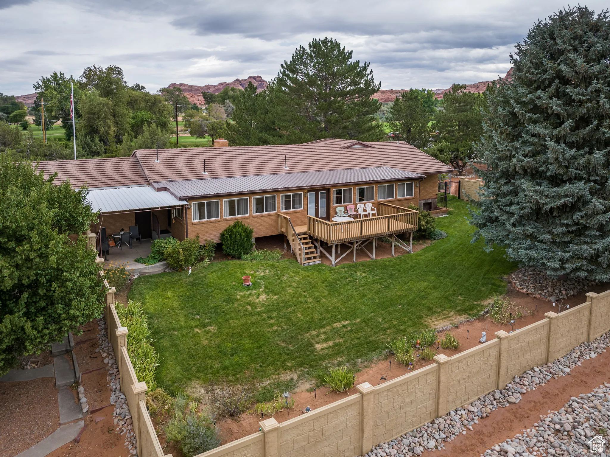 Back of house with a patio, stairs, a deck, brick siding, and a metal roof