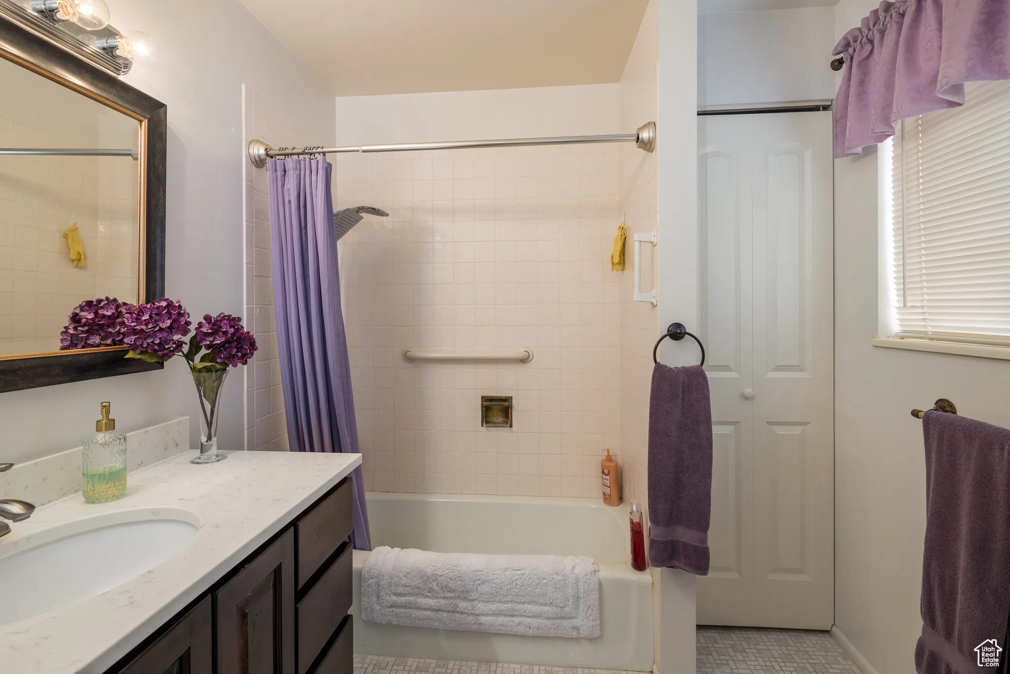 Bathroom featuring shower / bath combo with shower curtain, vanity, and a closet