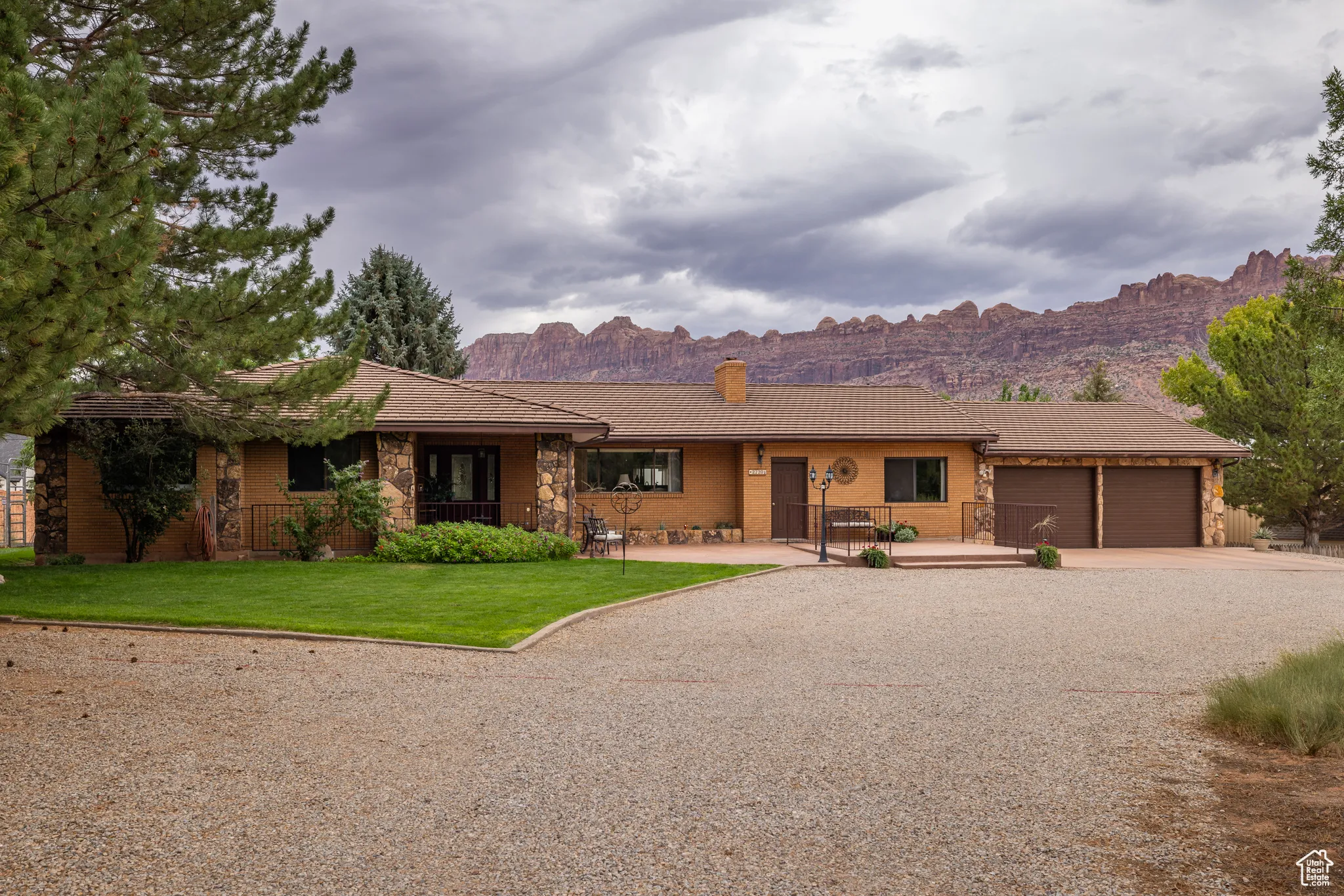Ranch-style house featuring a mountain view, driveway, an attached garage, a front yard, and stone siding