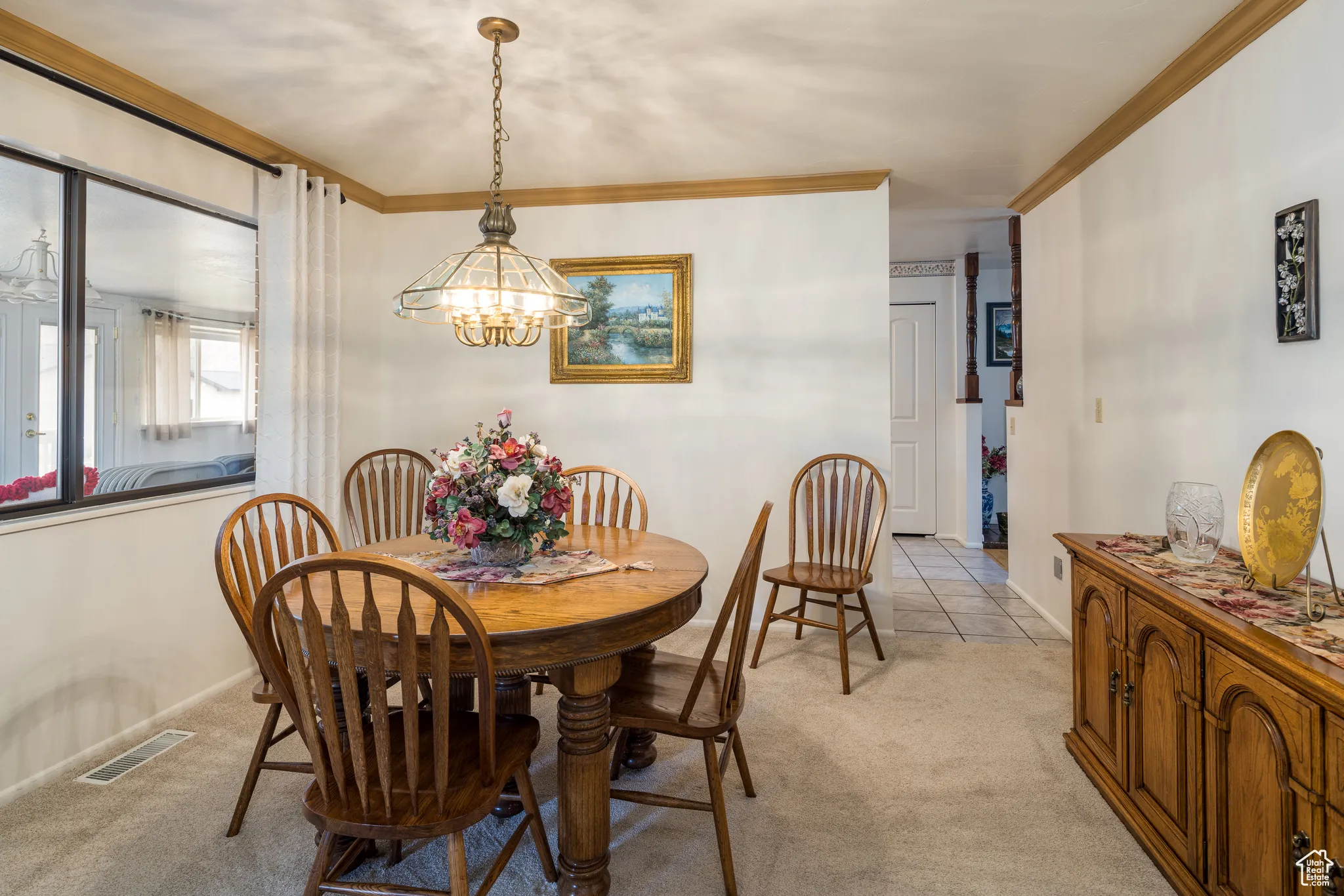 Dining space featuring light carpet, ornamental molding, and a chandelier