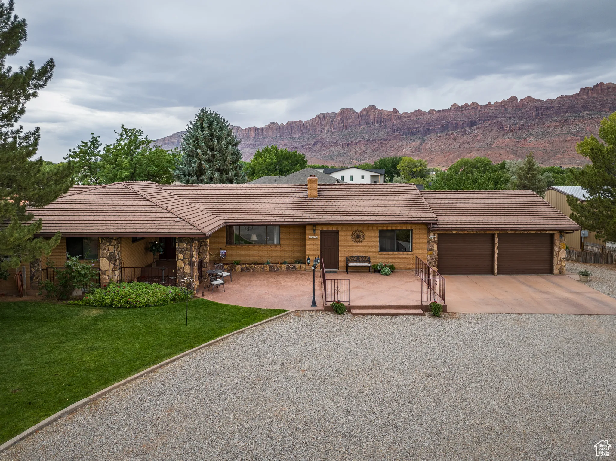View of front of property featuring stone siding, driveway, a garage, and a tiled roof
