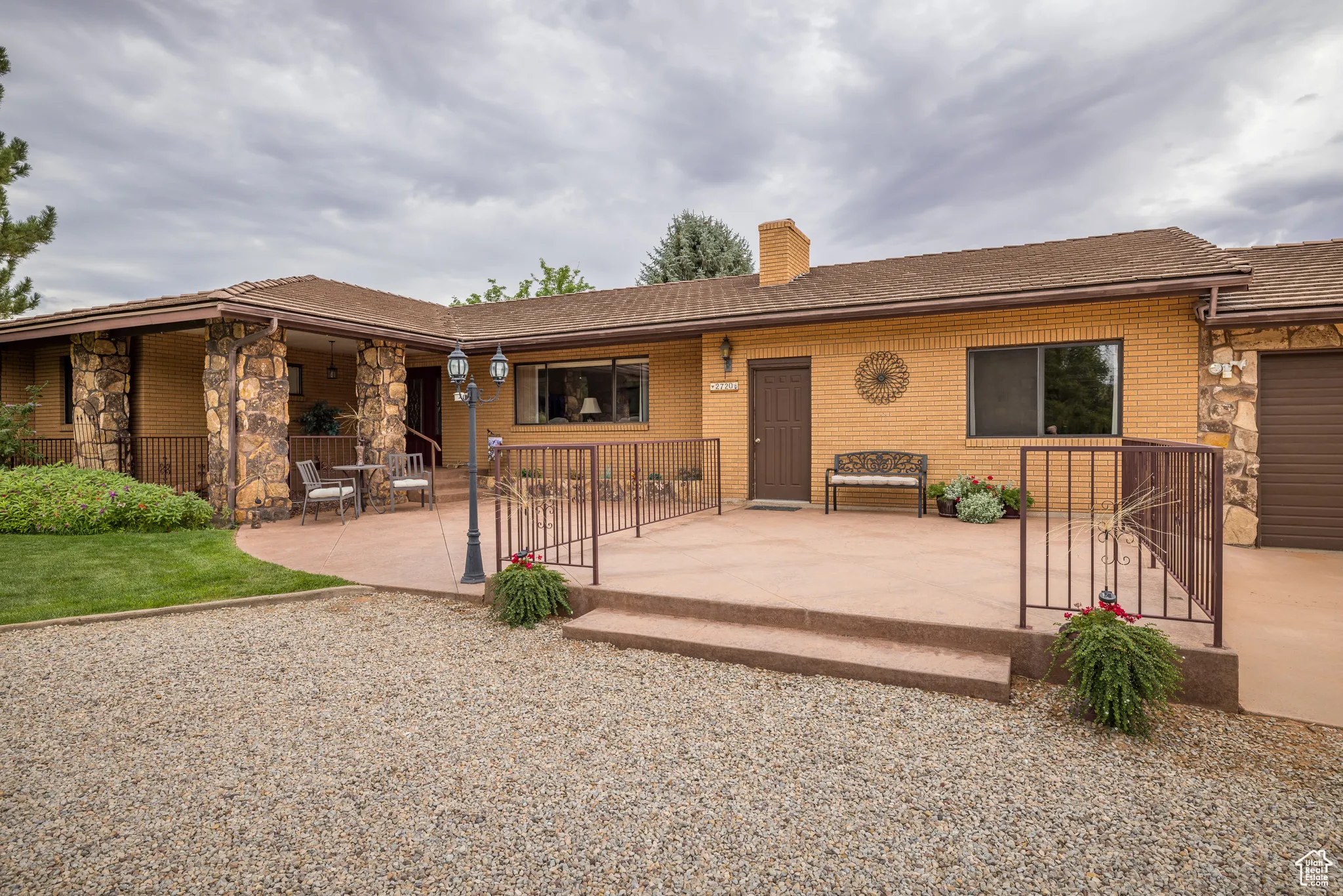 Single story home with a patio, a chimney, an attached garage, and brick siding
