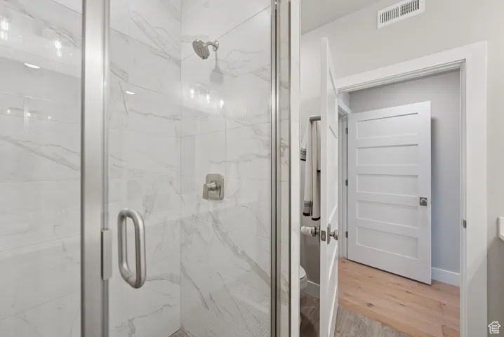 Full bathroom featuring a marble finish shower and light wood finished floors