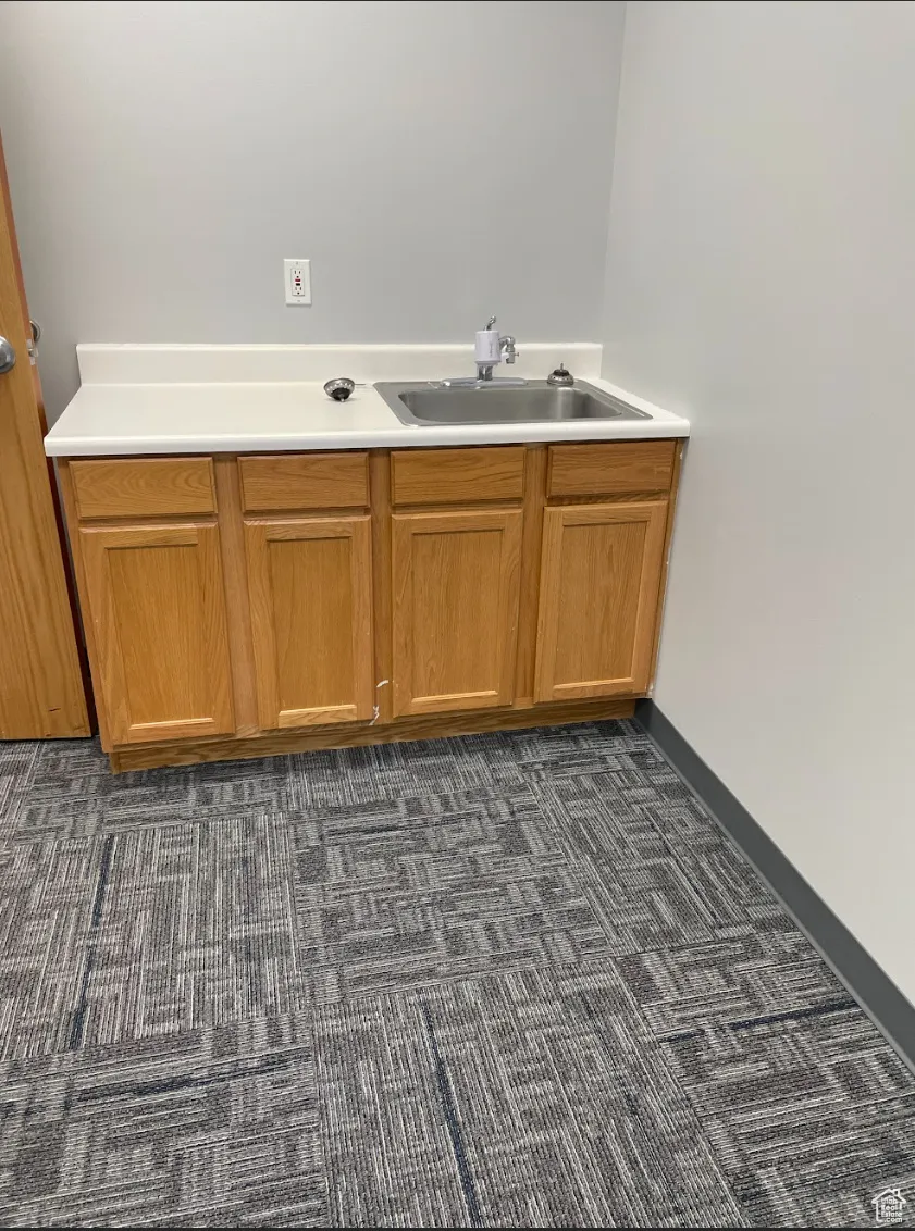 Bar area with light countertops, dark colored carpet, and brown cabinets