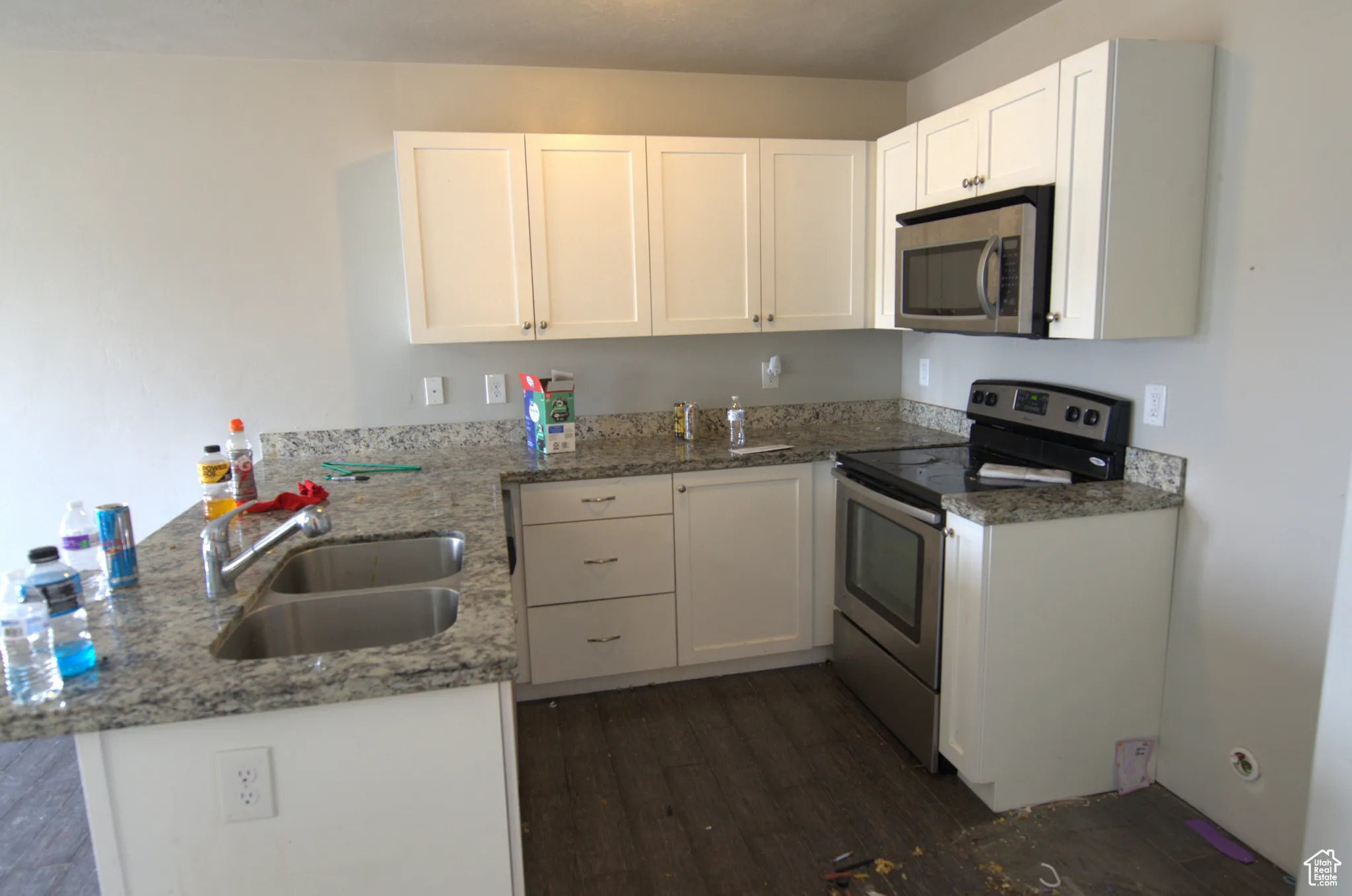 Kitchen featuring a peninsula, appliances with stainless steel finishes, white cabinetry, dark wood finished floors, and dark stone countertops
