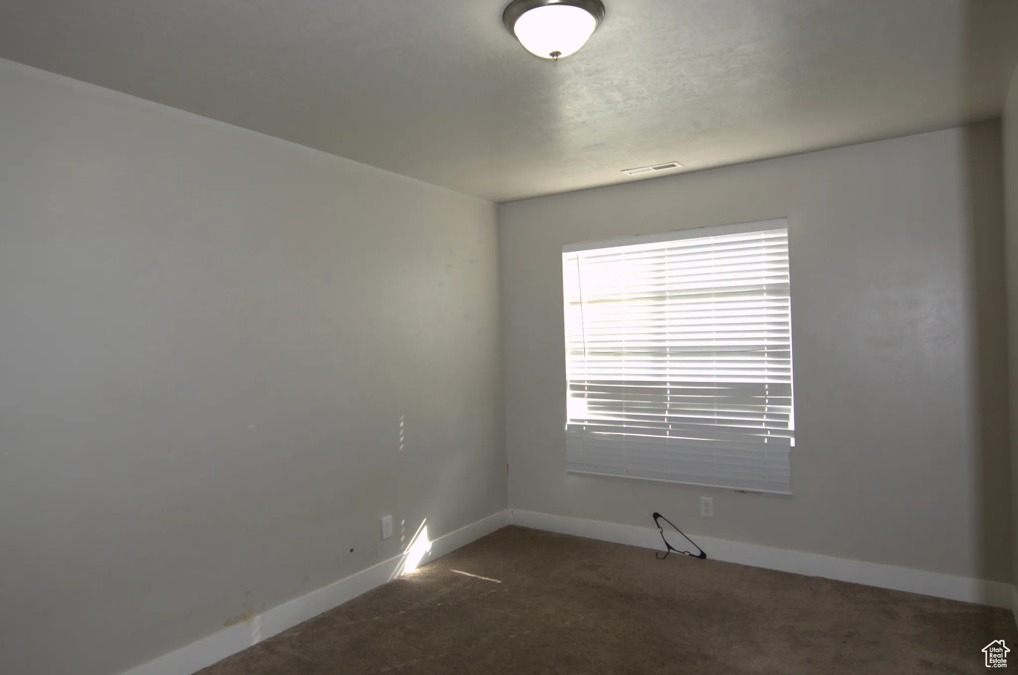 Empty room featuring dark carpet and baseboards