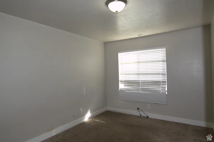 Empty room featuring dark carpet and baseboards