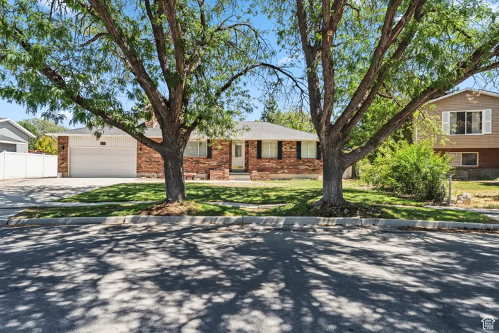 View of front of home with concrete driveway, an attached garage, brick siding, and roof with shingles