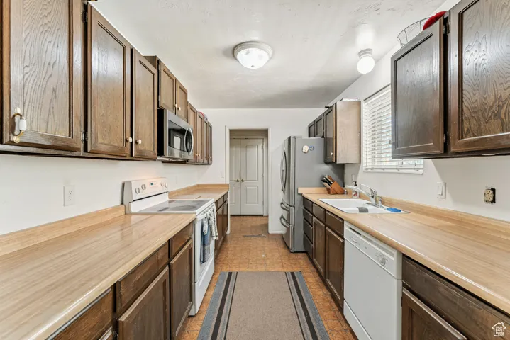 Kitchen featuring stainless steel appliances, light countertops, and dark brown cabinetry