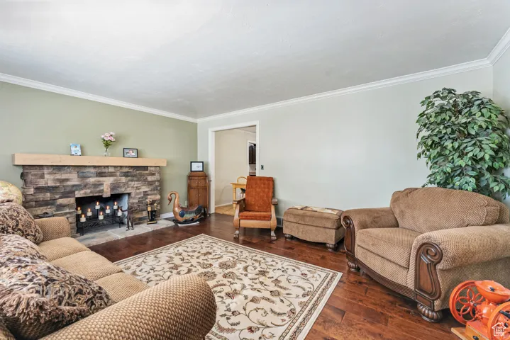 Living room with hardwood / wood-style flooring, crown molding, and a fireplace