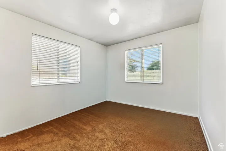 Unfurnished room with dark carpet and baseboards