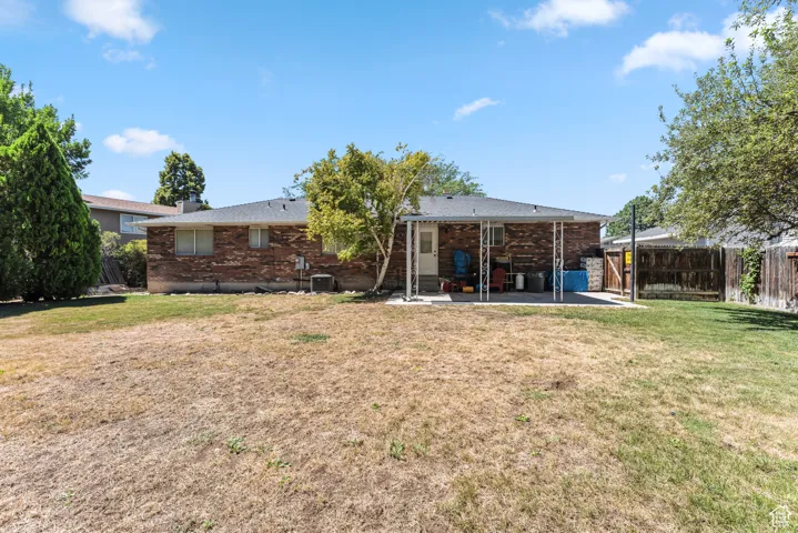 Back of house featuring brick siding, a patio area, and a fenced backyard