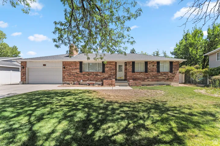 Ranch-style home with brick siding, concrete driveway, an attached garage, and a chimney