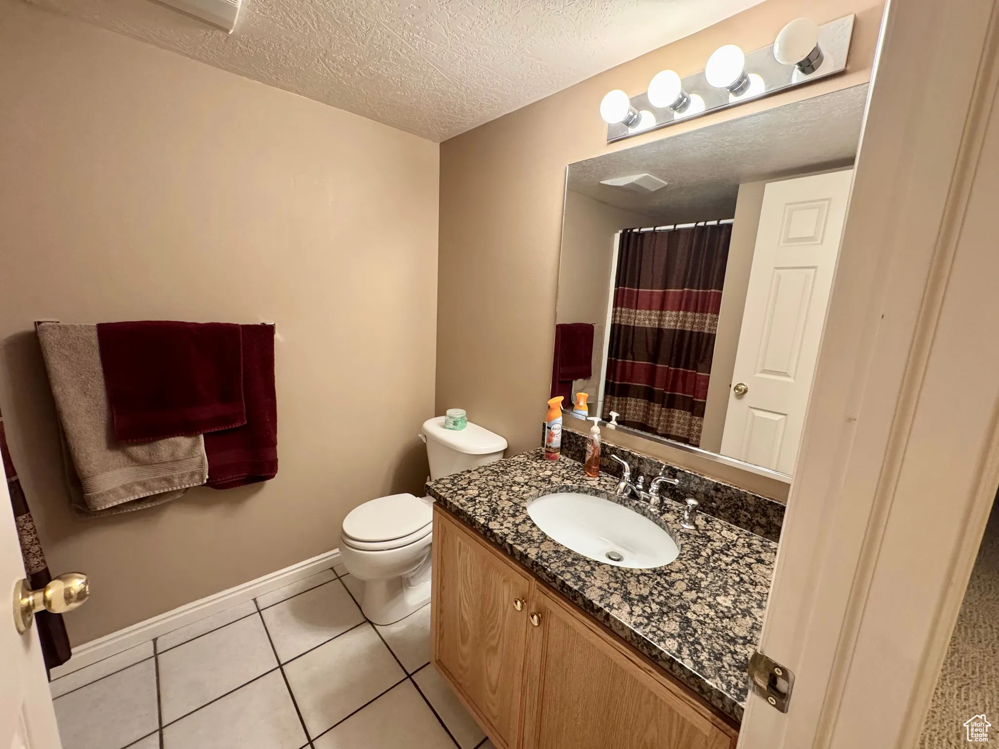 Bathroom with vanity, a textured ceiling, light tile patterned floors, and a shower with shower curtain