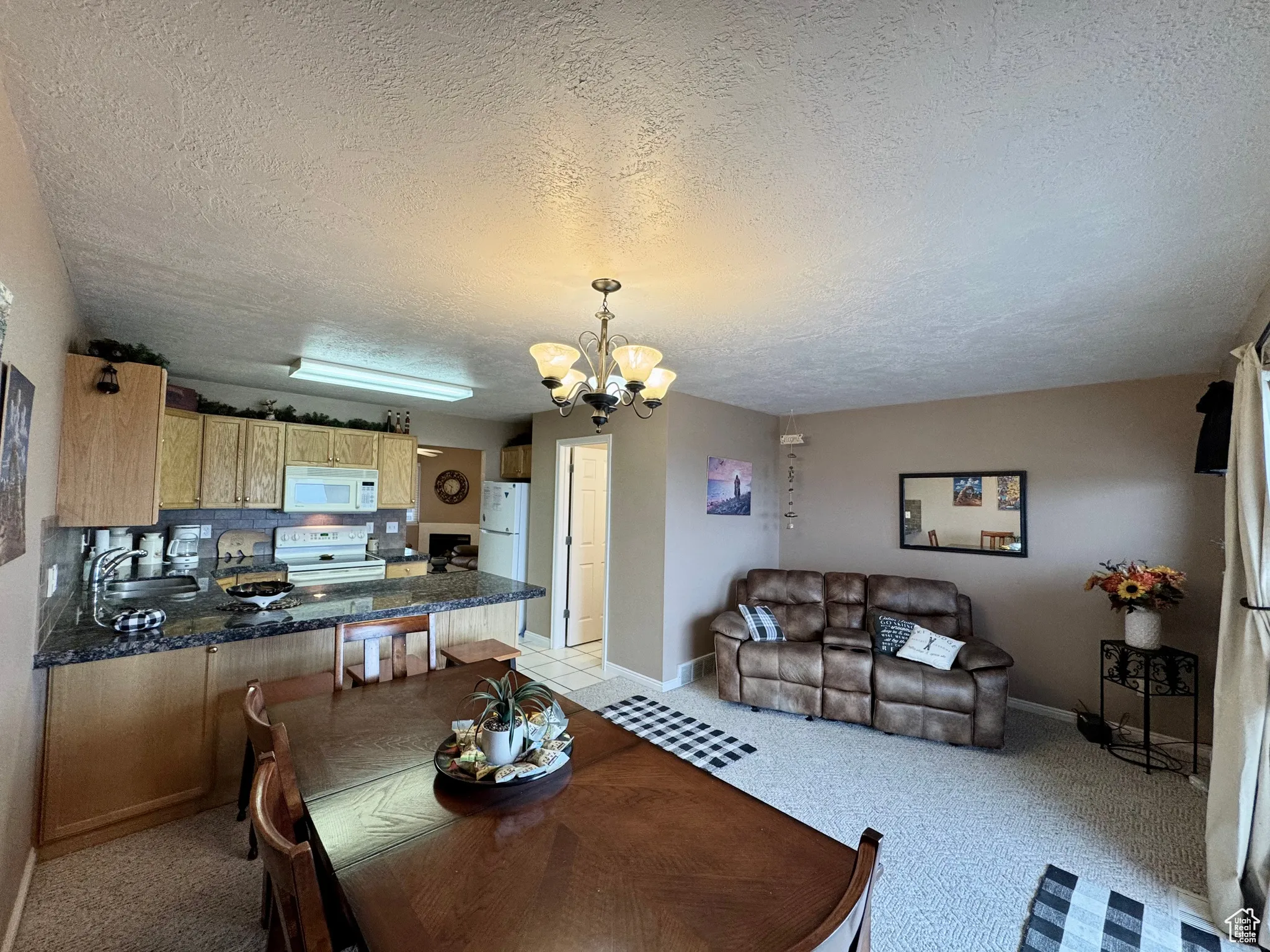 Dining room with a chandelier, a textured ceiling, and light colored carpet