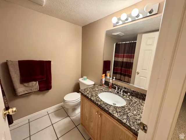 Bathroom with vanity, a textured ceiling, light tile patterned floors, and a shower with shower curtain