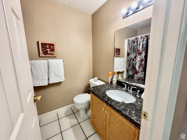 Bathroom featuring vanity, light tile patterned flooring, a textured ceiling, and curtained shower