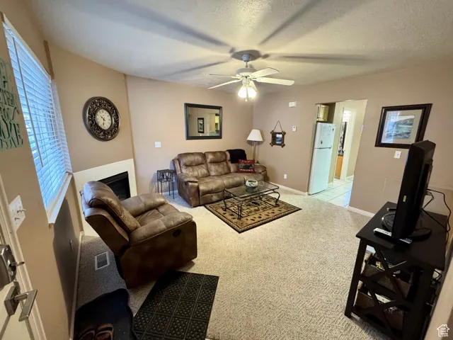 Carpeted living room featuring a textured ceiling and ceiling fan