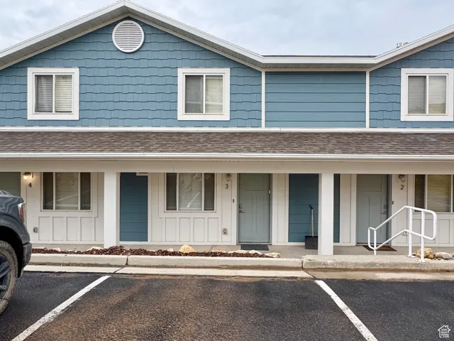 View of front facade with covered porch, board and batten siding, and uncovered parking