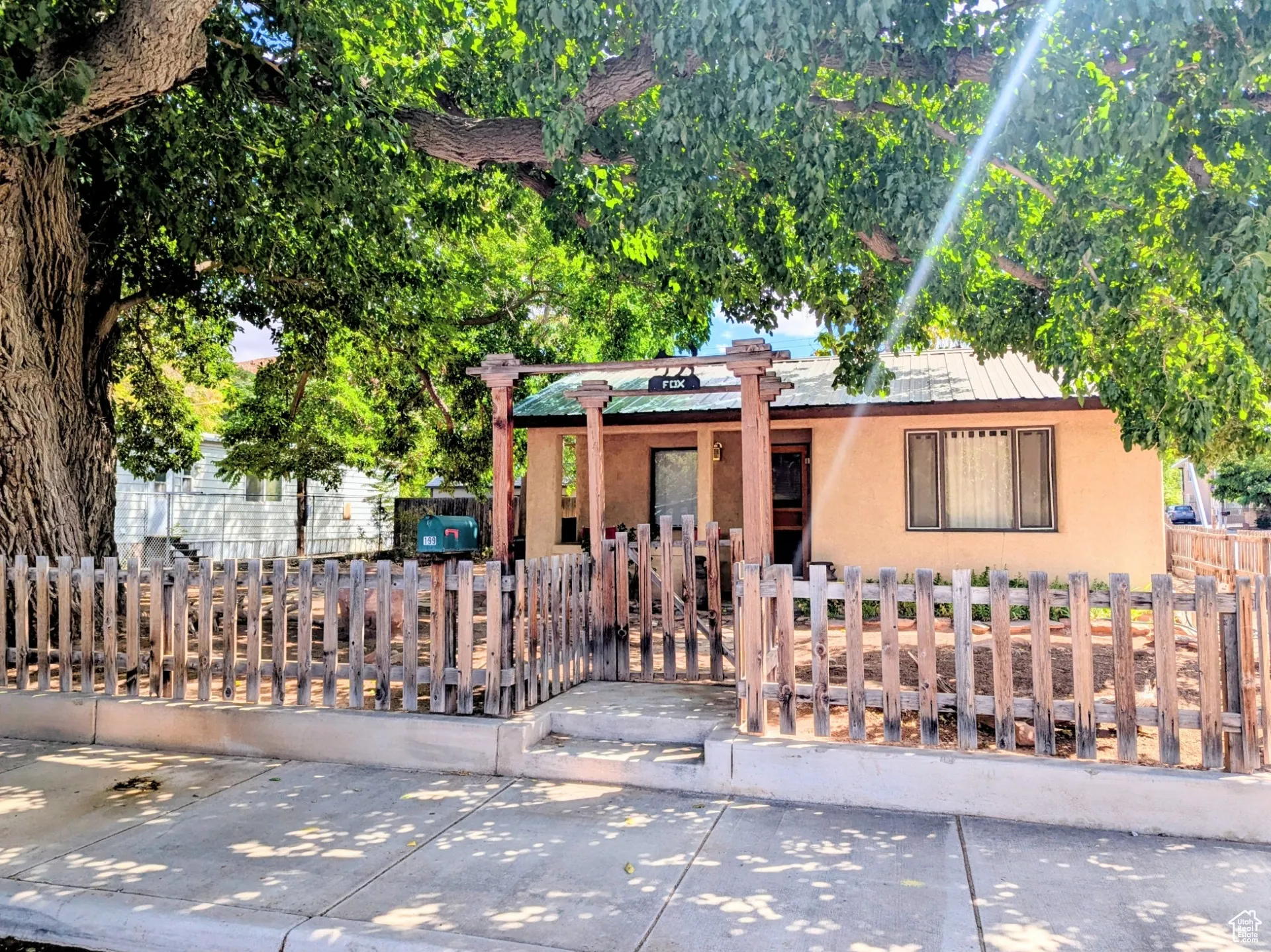 View of front of home with stucco siding, a metal roof, a fenced front yard, and a gate