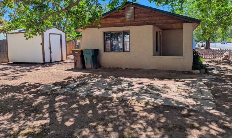 Back of property with stucco siding and a storage shed