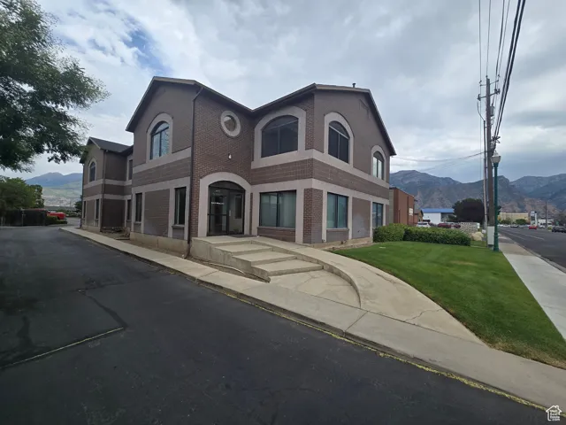 View of front of property featuring brick siding, a mountain view, and a front lawn