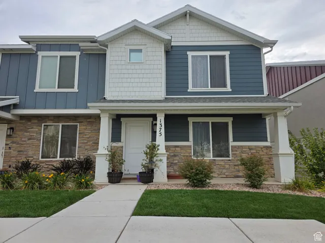 Craftsman-style home with a porch, stone siding, and a front lawn