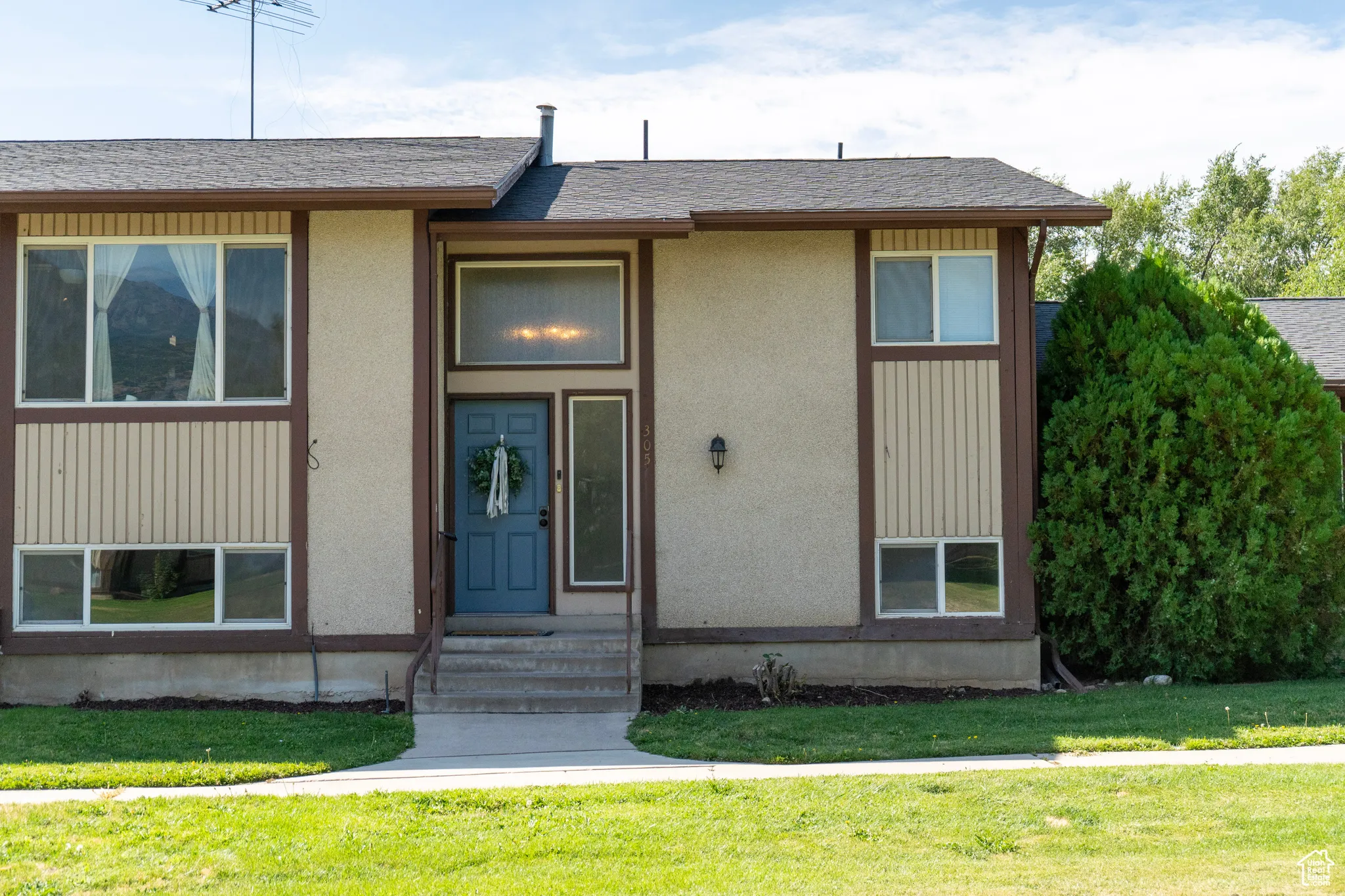 View of front of home with a front lawn, a shingled roof, and stucco siding
