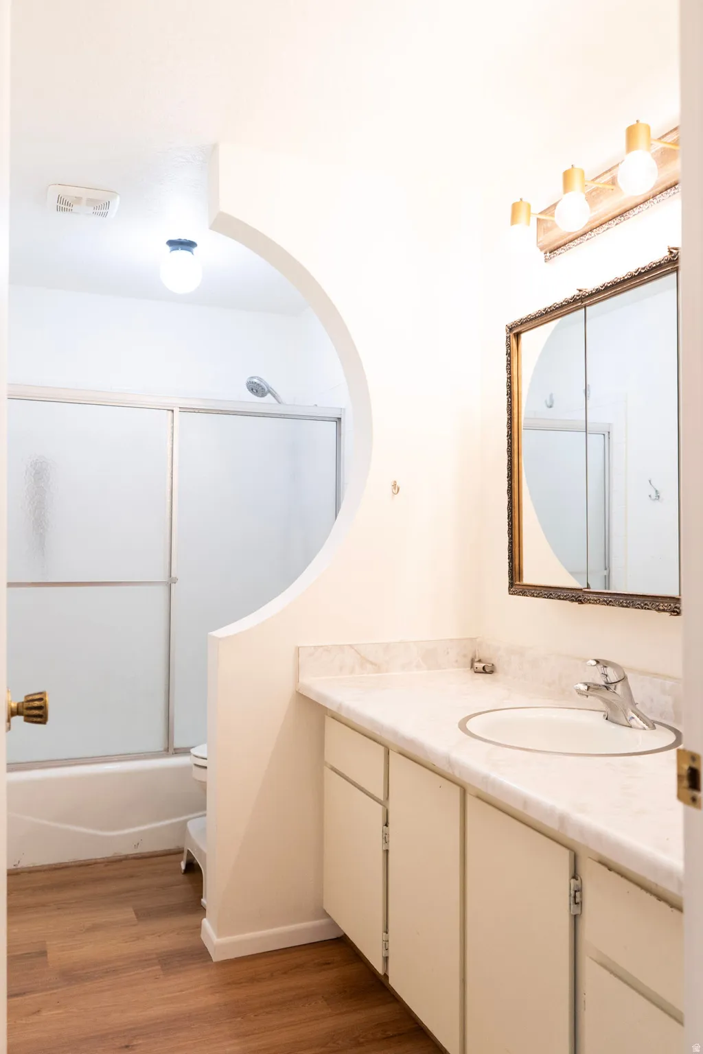 Bathroom featuring vanity, dark wood finished floors, and combined bath / shower with glass door