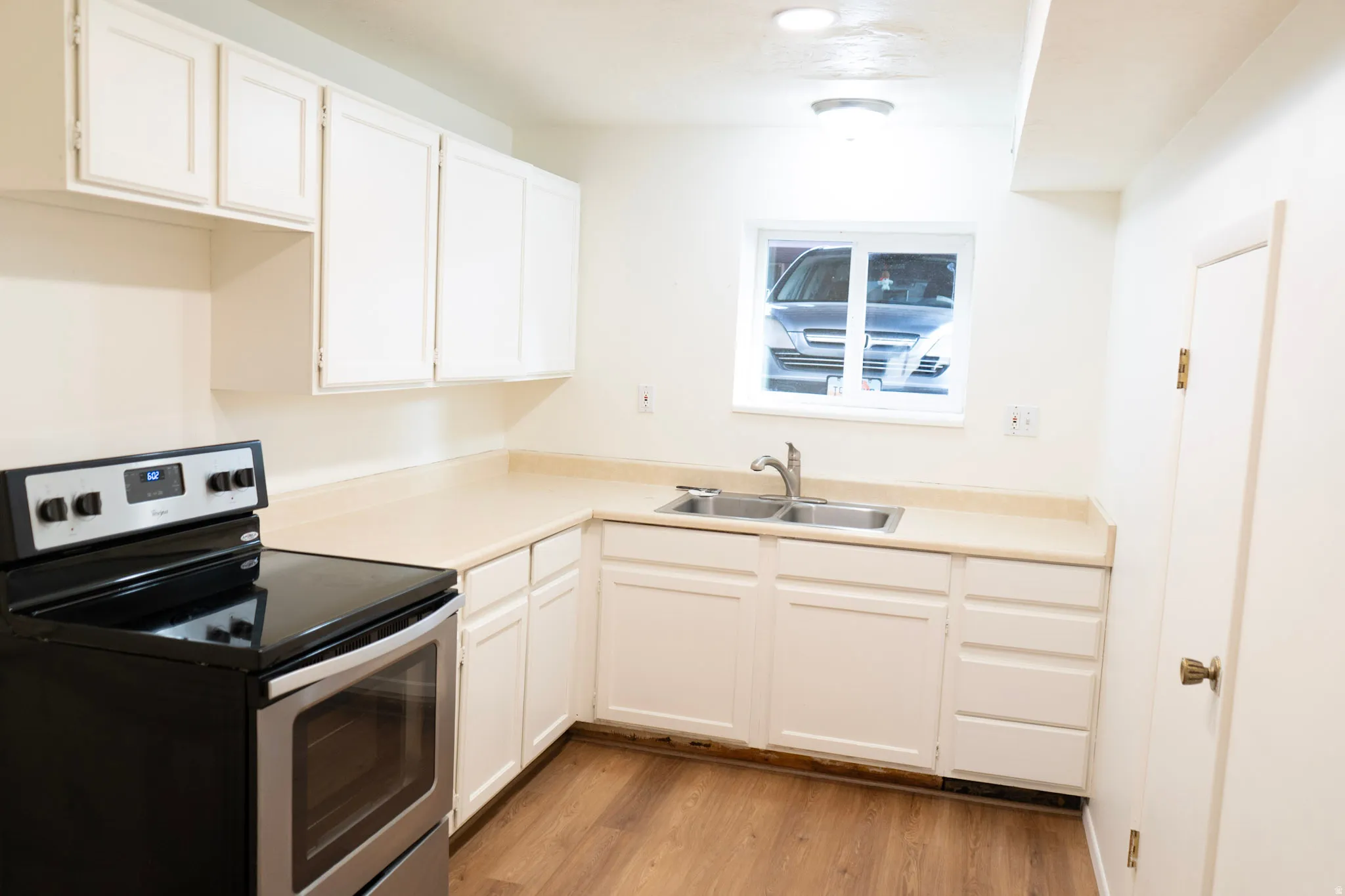 Kitchen with stainless steel range with electric stovetop, white cabinetry, and light countertops