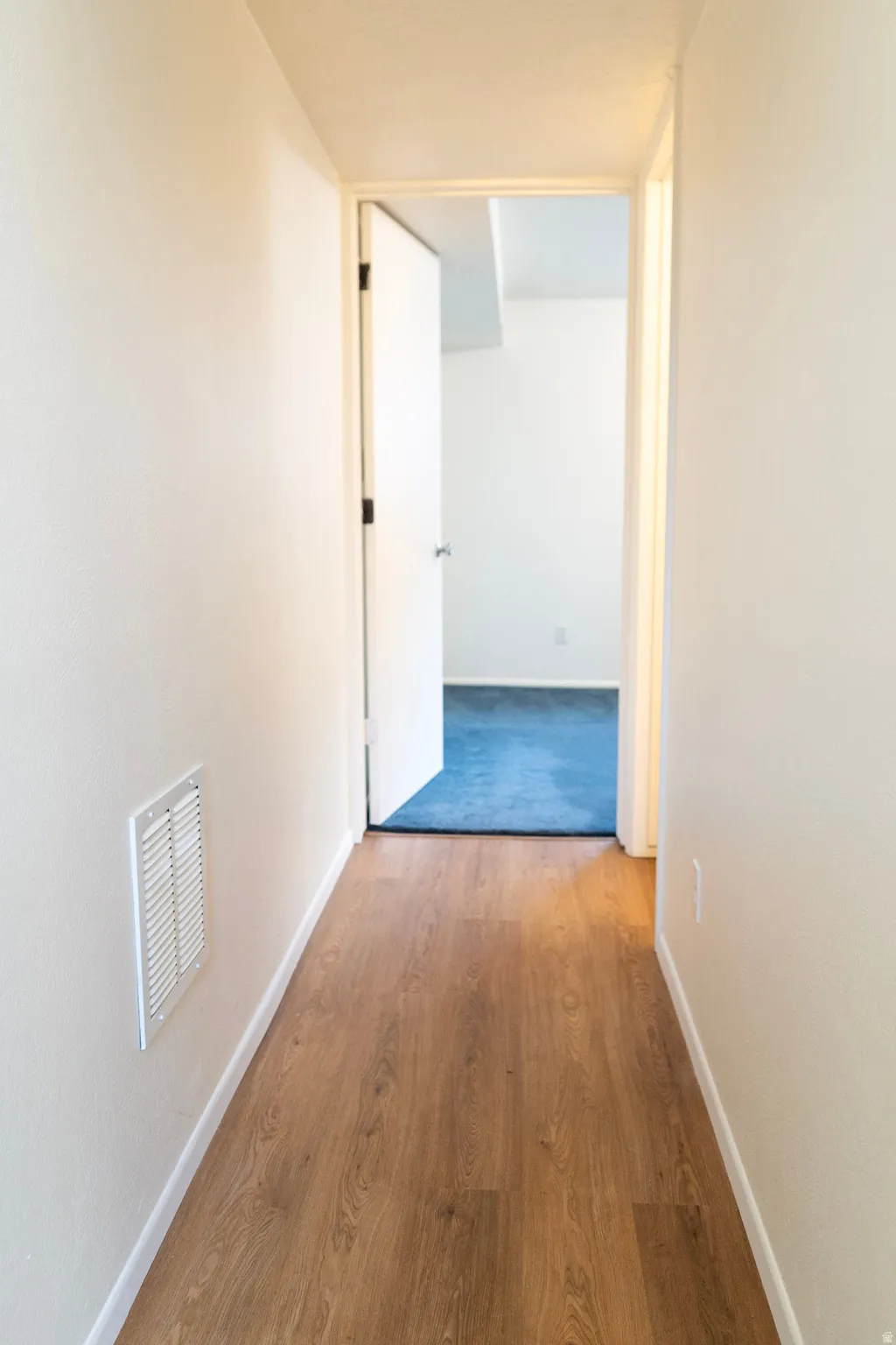 Corridor with light wood-style floors and baseboards