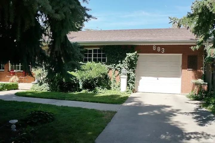 View of front of home featuring concrete driveway, a shingled roof, a garage, and brick siding
