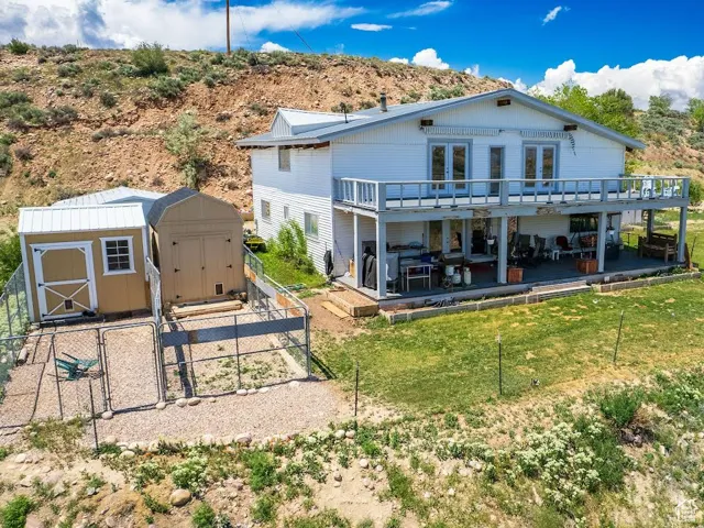 Back of property featuring a shed, a wooden deck, and a gate