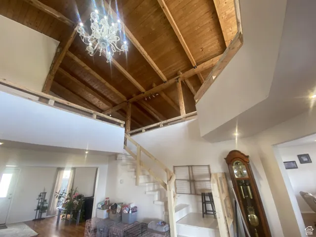 Stairs featuring a wooden ceiling with exposed beams, high vaulted ceiling, and wood finished floors