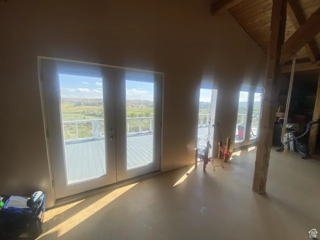 Doorway to outside featuring french doors, beam ceiling, concrete floors, and high vaulted ceiling