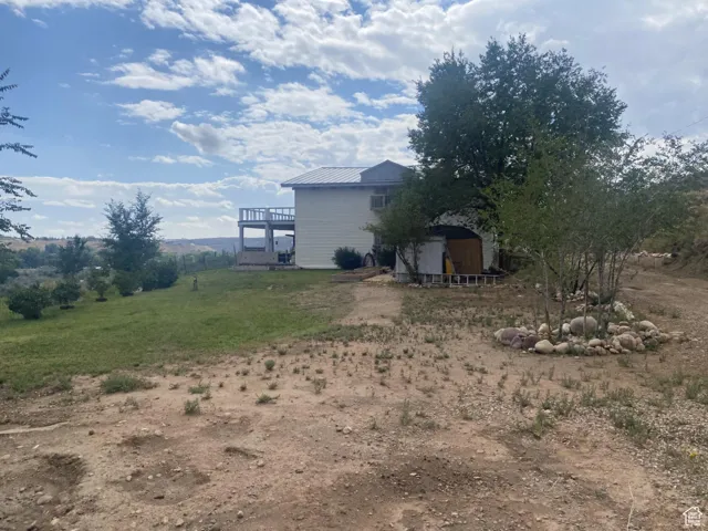 View of grassy yard with a deck and a storage unit