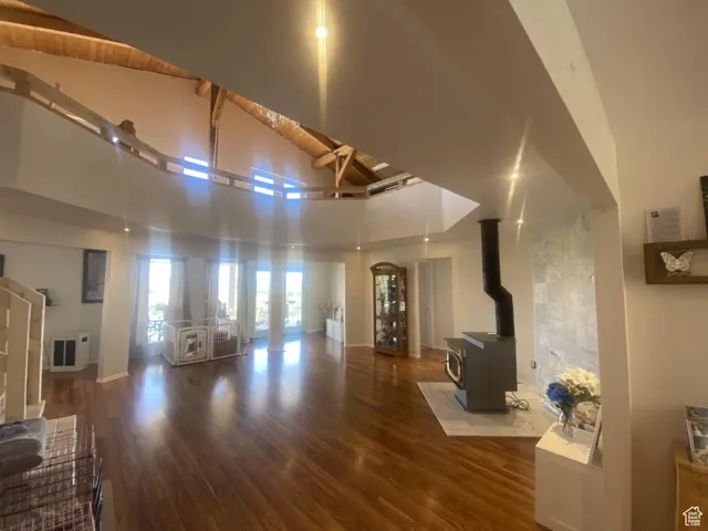 Unfurnished living room featuring a wood stove, dark wood-type flooring, and high vaulted ceiling