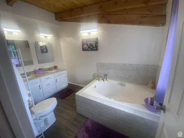 Full bath featuring vanity, a bath, dark wood-style floors, and a wood ceiling with exposed beams