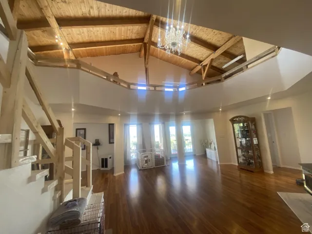 Living area featuring dark wood finished floors, high vaulted ceiling, a wood ceiling with exposed beams, and stairs