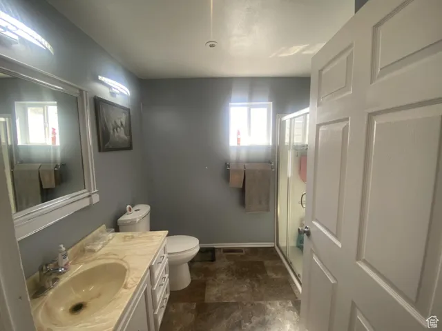 Bathroom with vanity, a stall shower, and stone finish floors