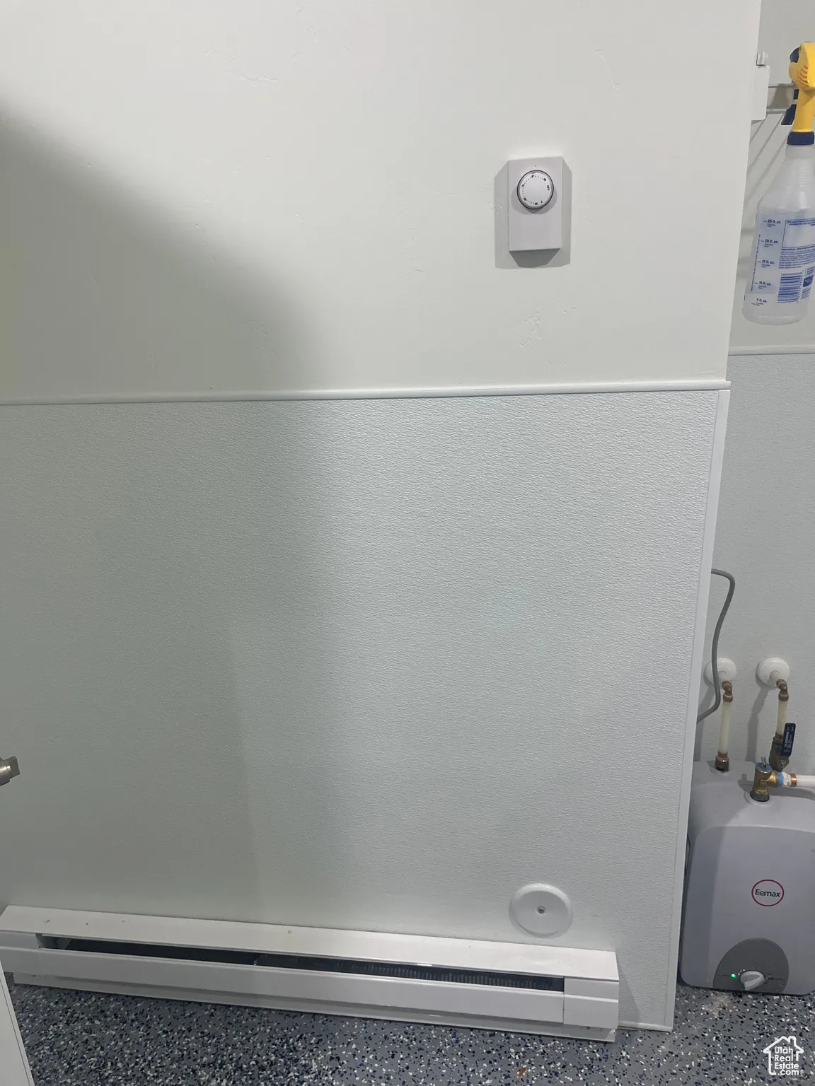 Detailed view of baseboard heating and speckle patterned floor
