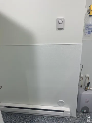 Detailed view of baseboard heating and speckle patterned floor